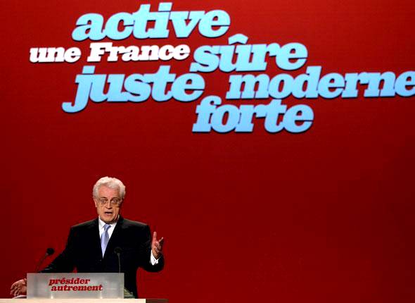 Jospin, en meeting, devant un fond rouge portant les mots "une France active, sûre, juste, moderne, forte"