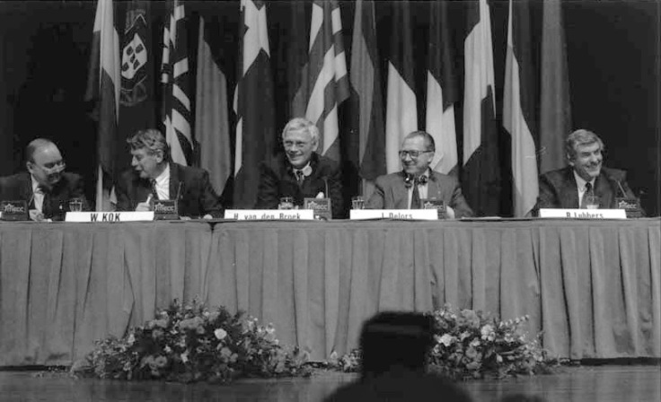 Photographie en noir et blanc représentant quatre hommes derrière une table pour une conférence de presse.